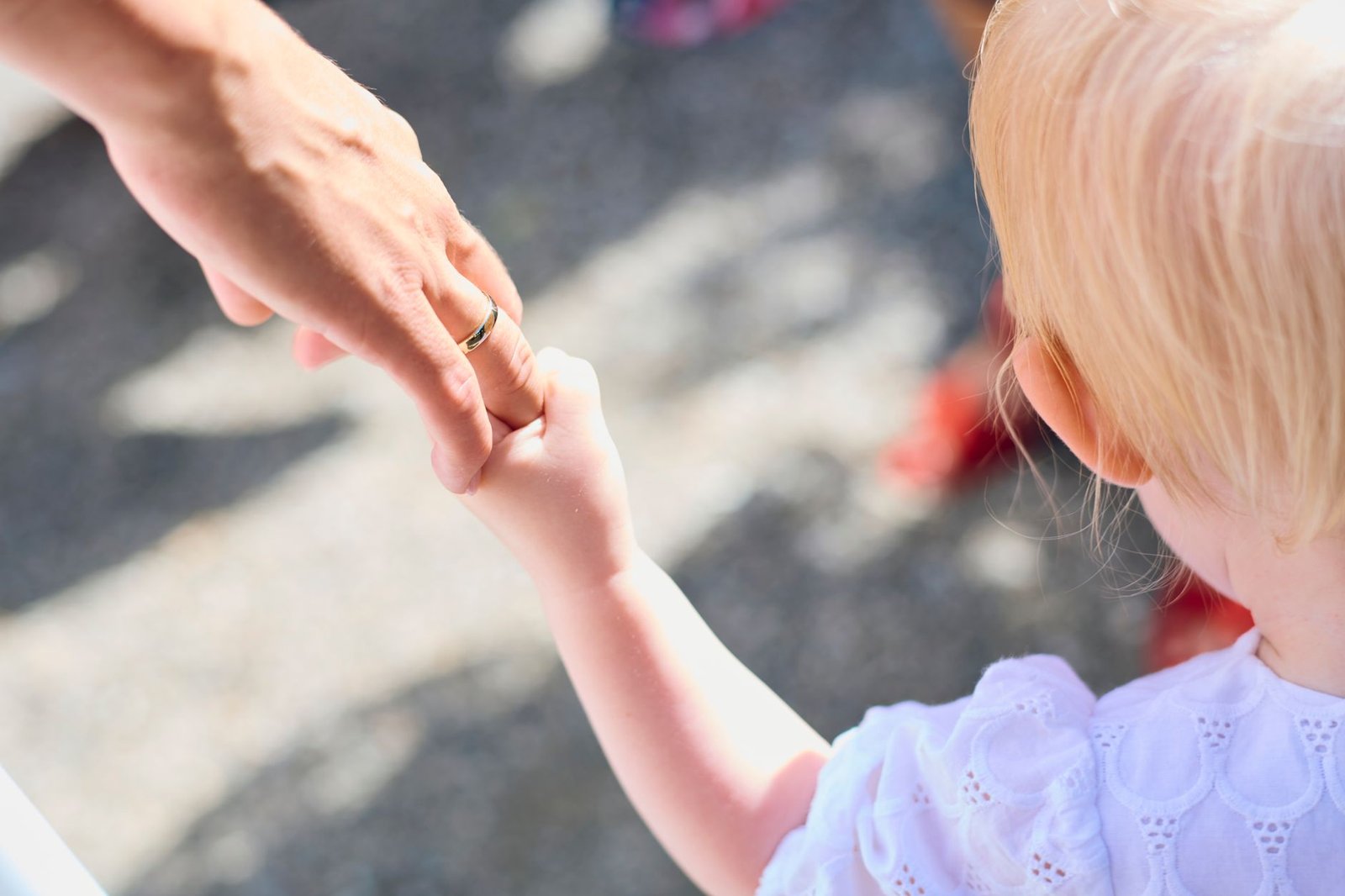 A child holding a parent's hand while walking outdoors
