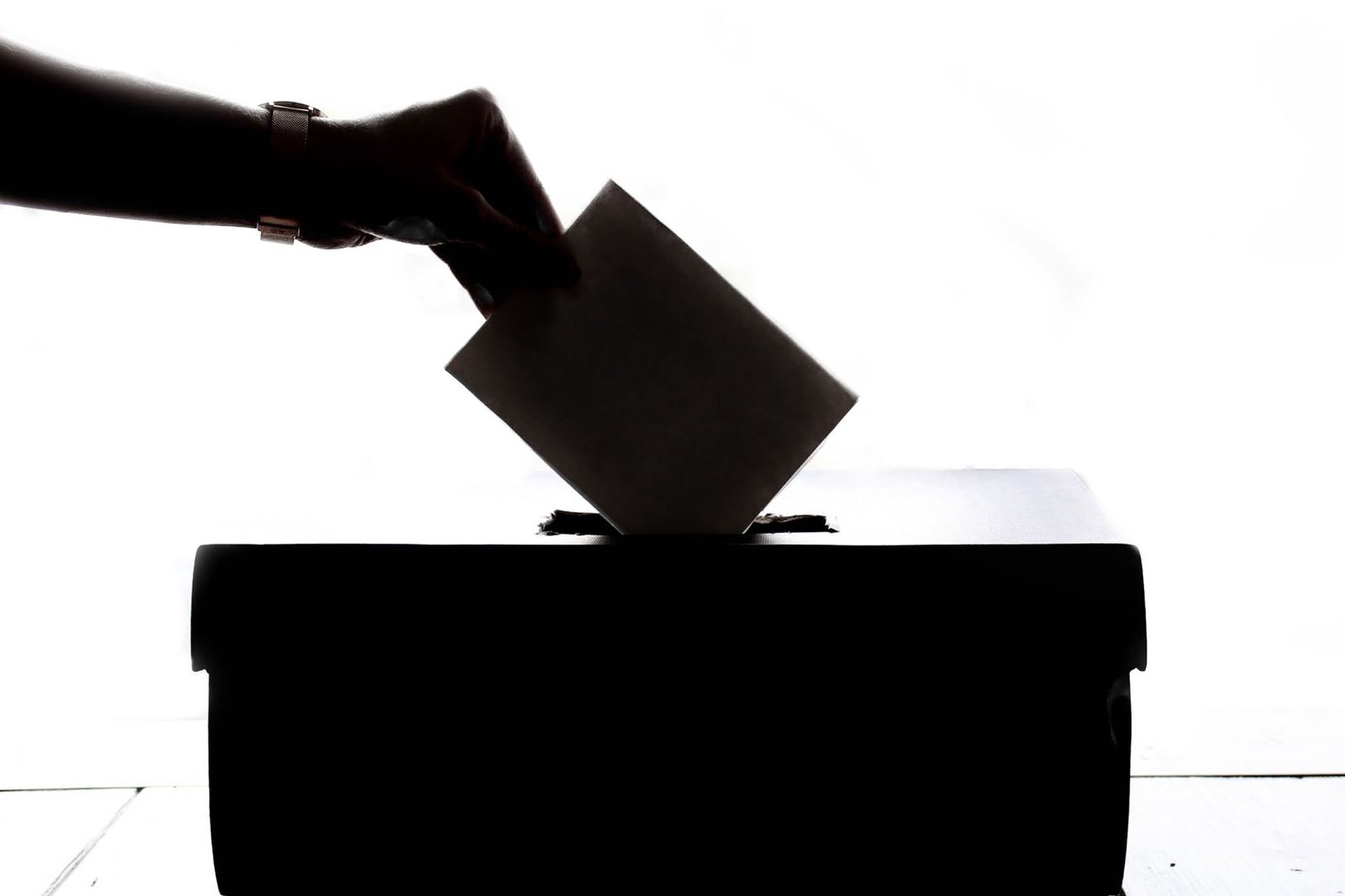 Silhouette of a voter placing a ballot into a voting box – referendum