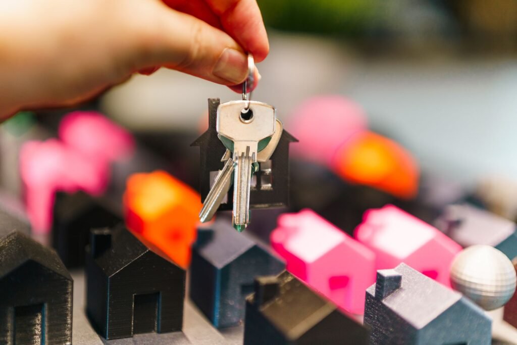 Colourful miniature houses and a hand holding keys – real estate decisions