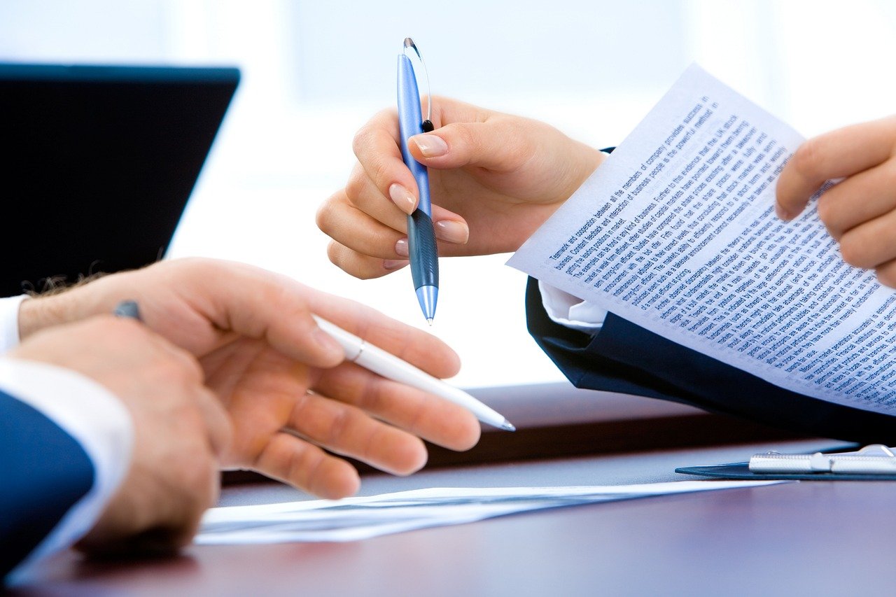 Hand writing on a document by a laptop – ordering a marriage certificate
