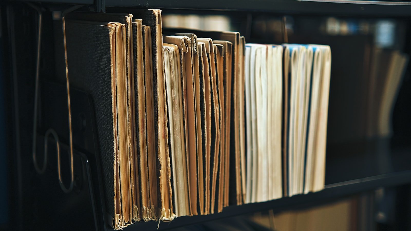 Old documents and books on a black metal library shelf