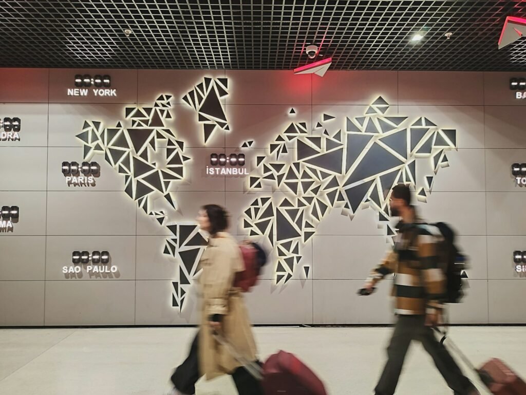 Two travellers with suitcases in front of a glowing world map